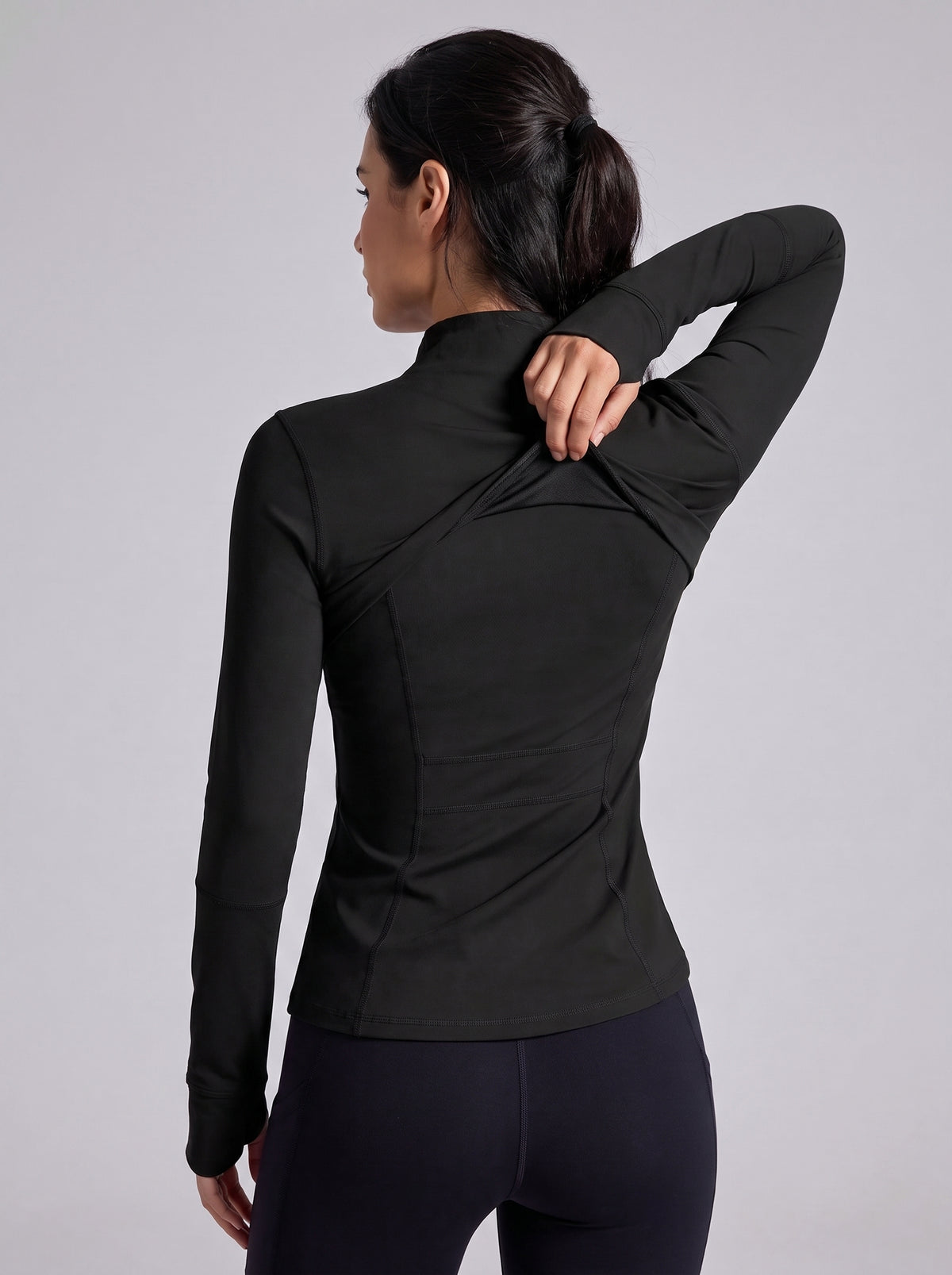 Chaqueta técnica negra entallada vista trasera con cremallera y cuello alto.