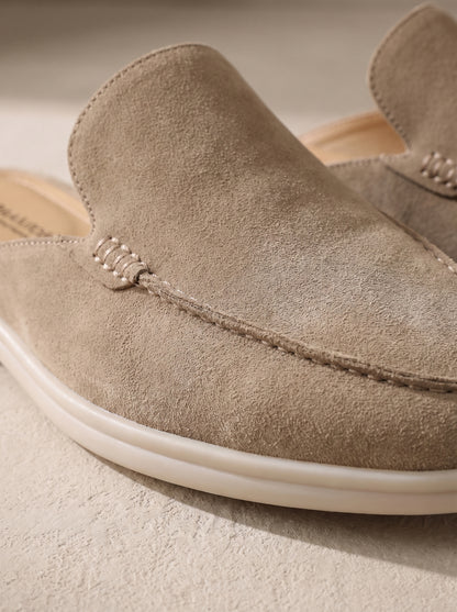 Mocasín mule de ante beige claro con costura en forma de cordón y suela blanca.