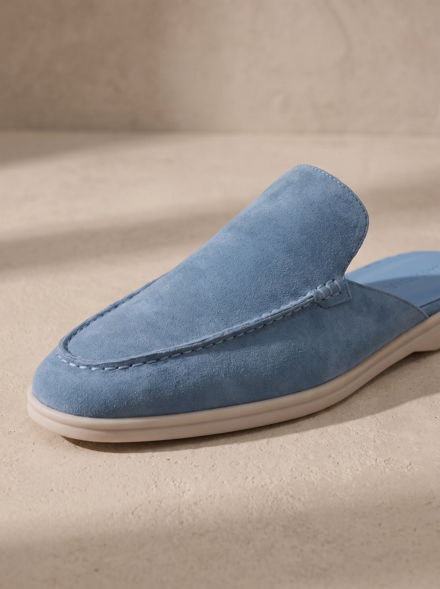 Mocasín mule de ante azul claro, vista lateral con costuras en la pala.