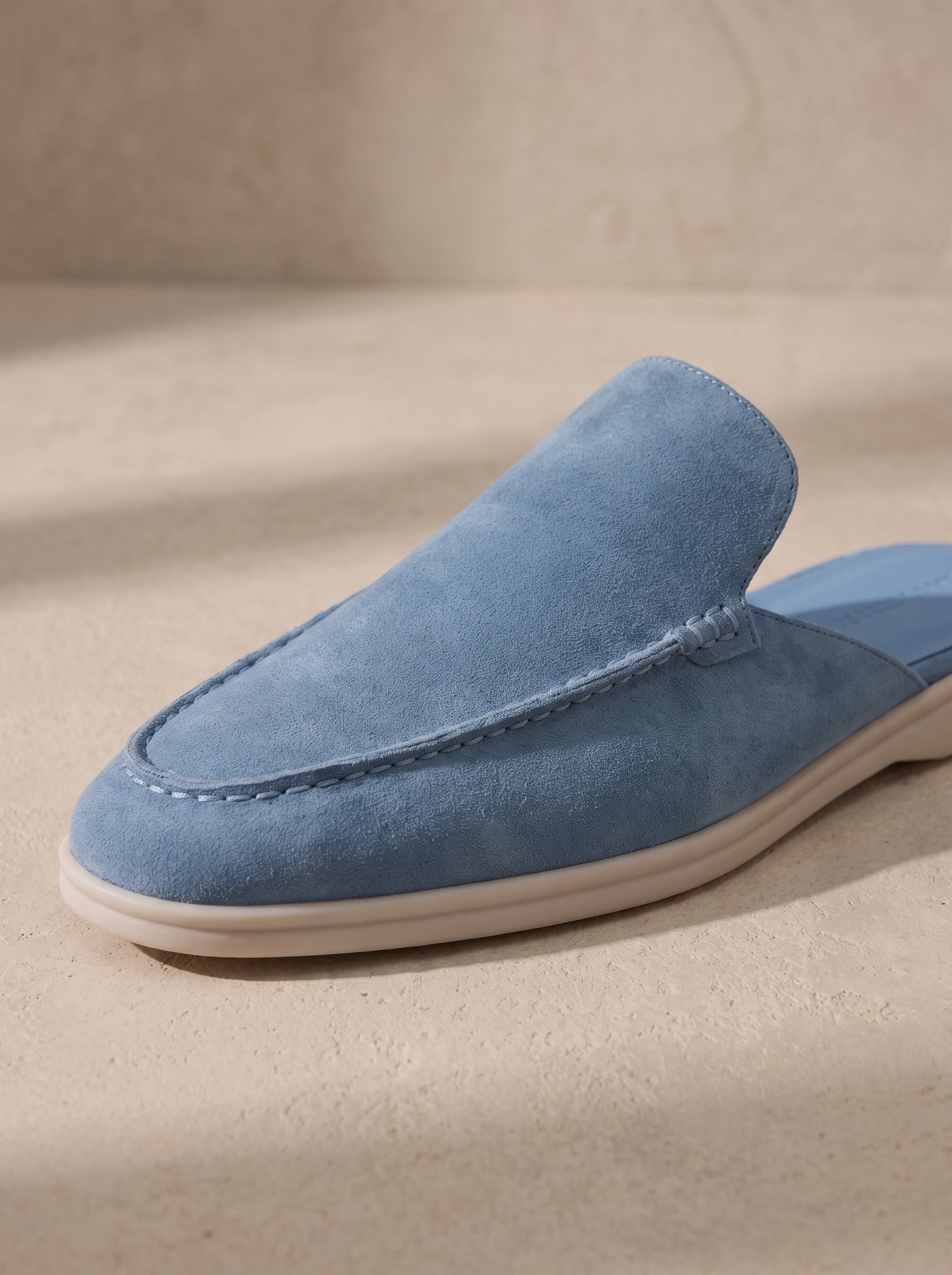 Mocasín mule de ante azul claro, vista lateral con costuras en la pala.