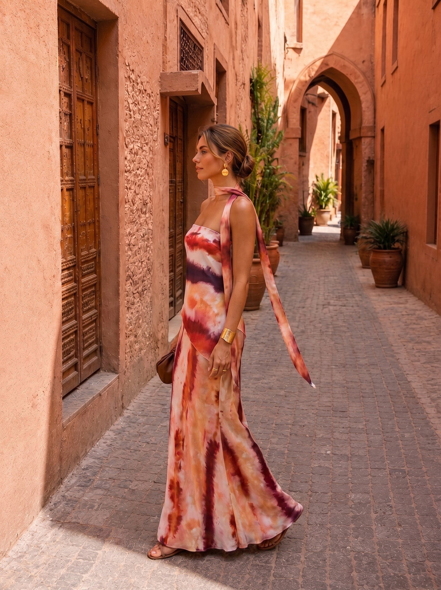 Vestido largo estampado con escote halter y tiras laterales; tonos terracota, blanco y morado.