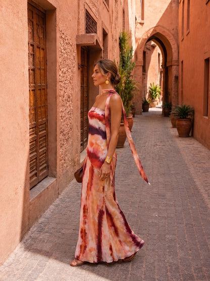Vestido largo estampado con escote halter y tiras laterales; tonos terracota, blanco y morado.