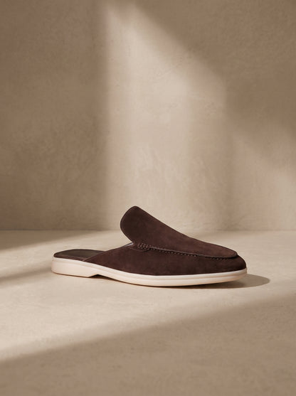 Mocasín mule de ante marrón oscuro con costuras y suela blanca.