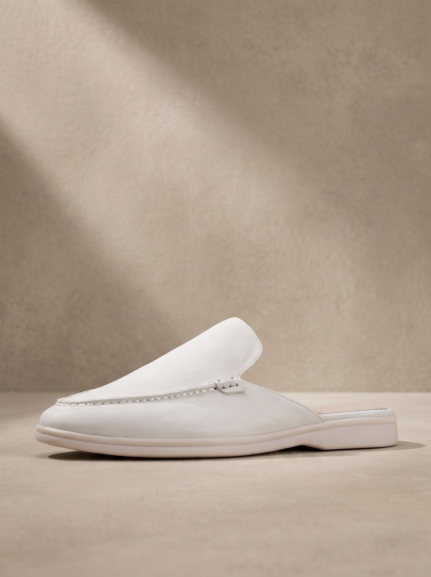 Mocasín mule de ante color blanco, con costuras y suela de goma blanca.