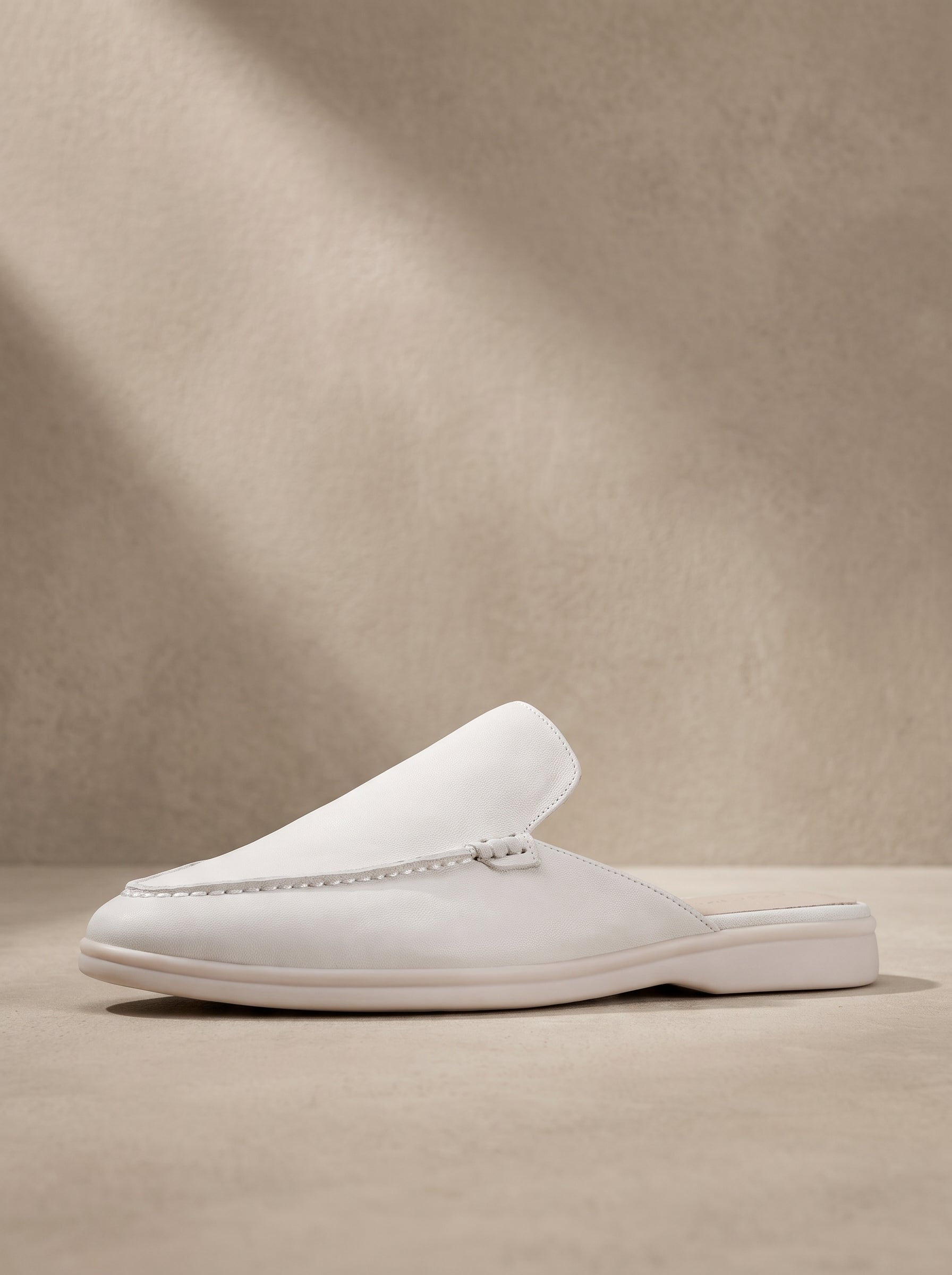 Mocasín mule de ante color blanco, con costuras y suela de goma blanca.
