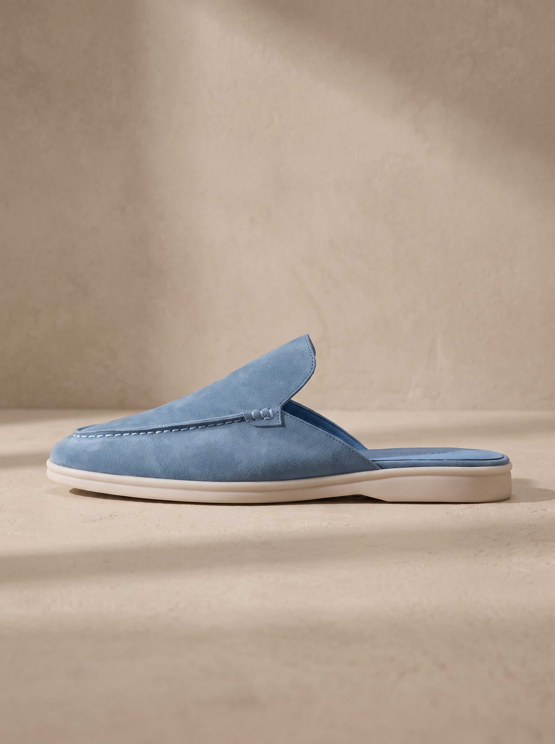 Mocasín mule de ante azul, diseño tipo zueco sin cierre, suela blanca.