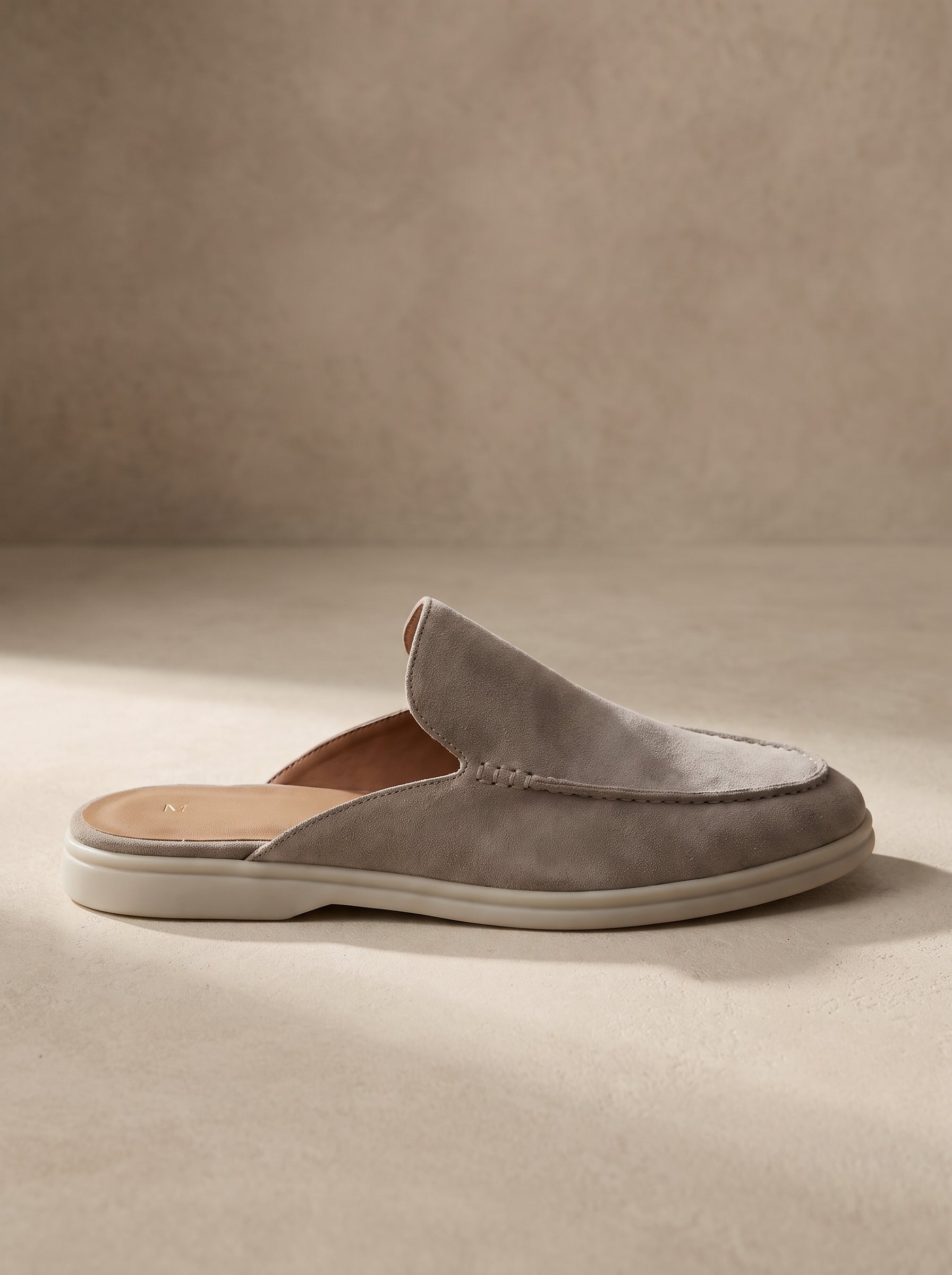 Mocasín mule de ante gris, diseño slip-on con suela blanca y pala ancha.