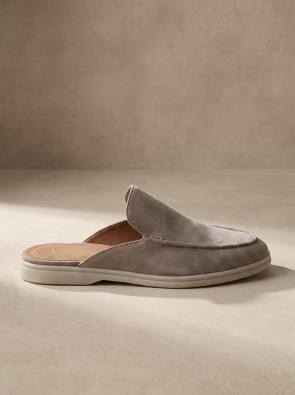 Mocasín mule de ante gris, diseño slip-on con suela blanca y pala ancha.