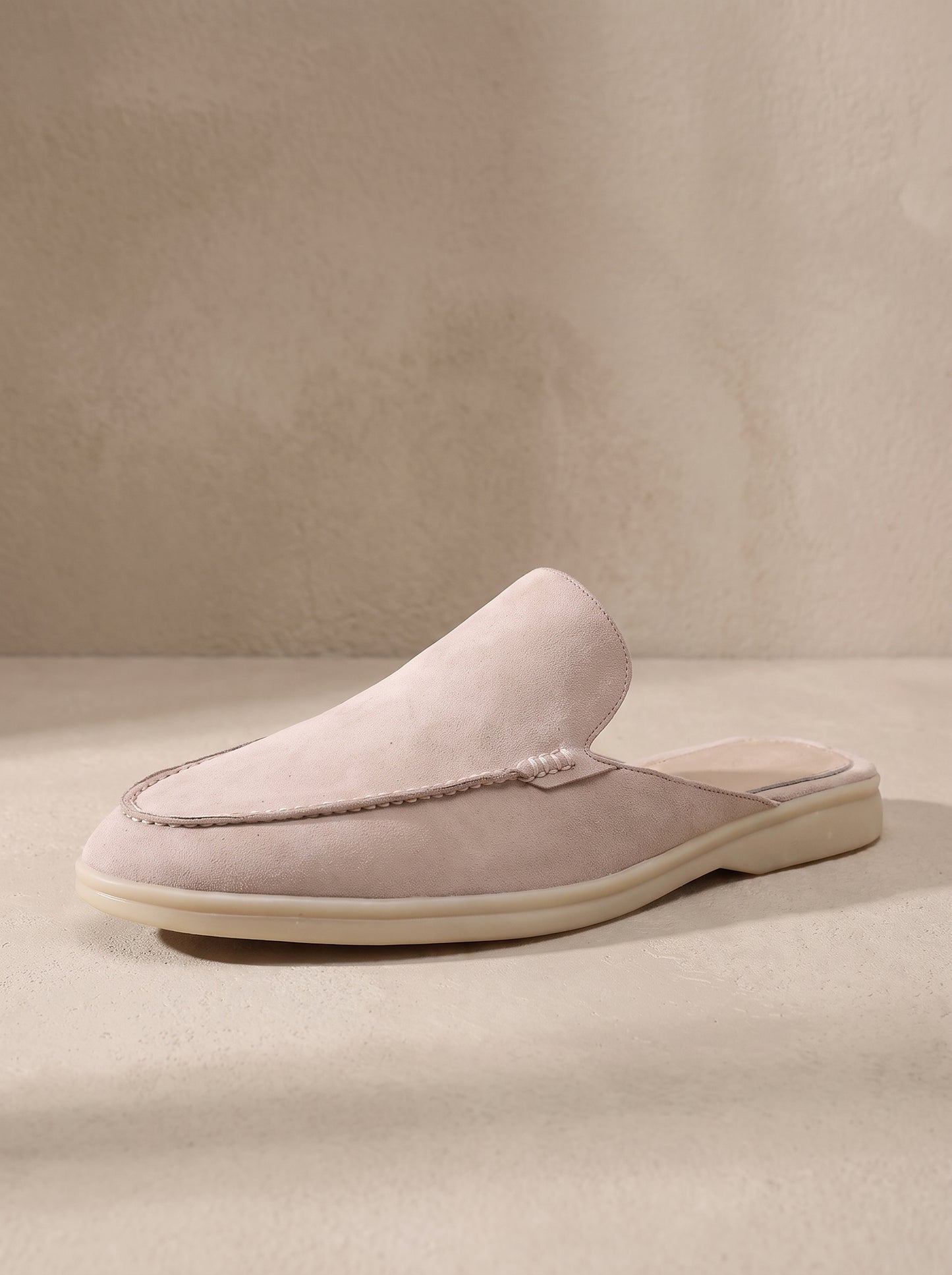 Mocasín mule de ante beige claro, slip-on, suela clara y pala sin cordones.