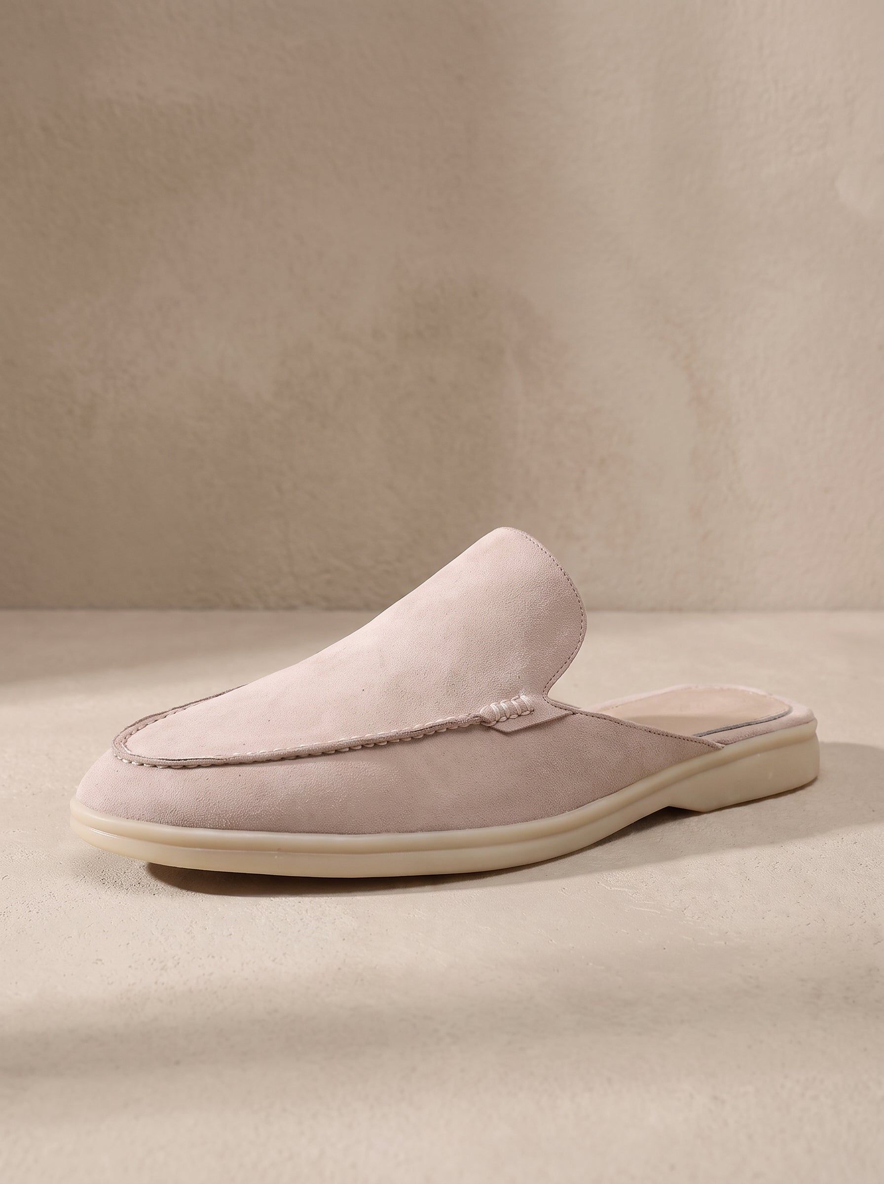 Mocasín mule de ante beige claro, slip-on, suela clara y pala sin cordones.