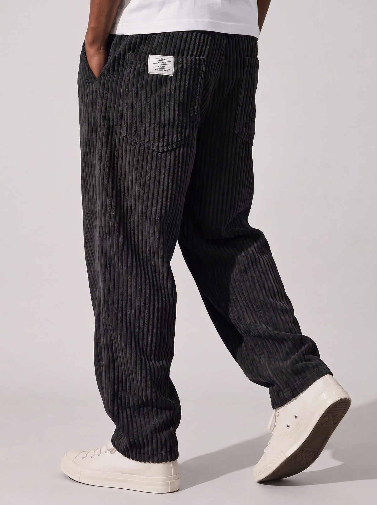 Pantalón de pana relajado negro, tiro medio, textura acanalada y bolsillos laterales.
