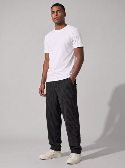 Pantalón de pana relajado negro, pierna recta y puño ajustado, look casual.