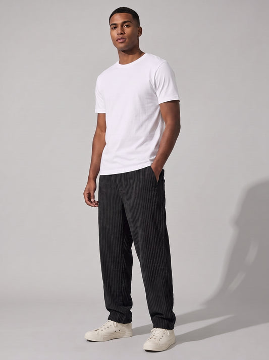Pantalón de pana relajado negro, pierna recta y puño ajustado, look casual.