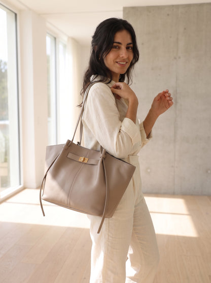 Bolso elegante beige tipo tote con hebilla dorada y cordones colgantes