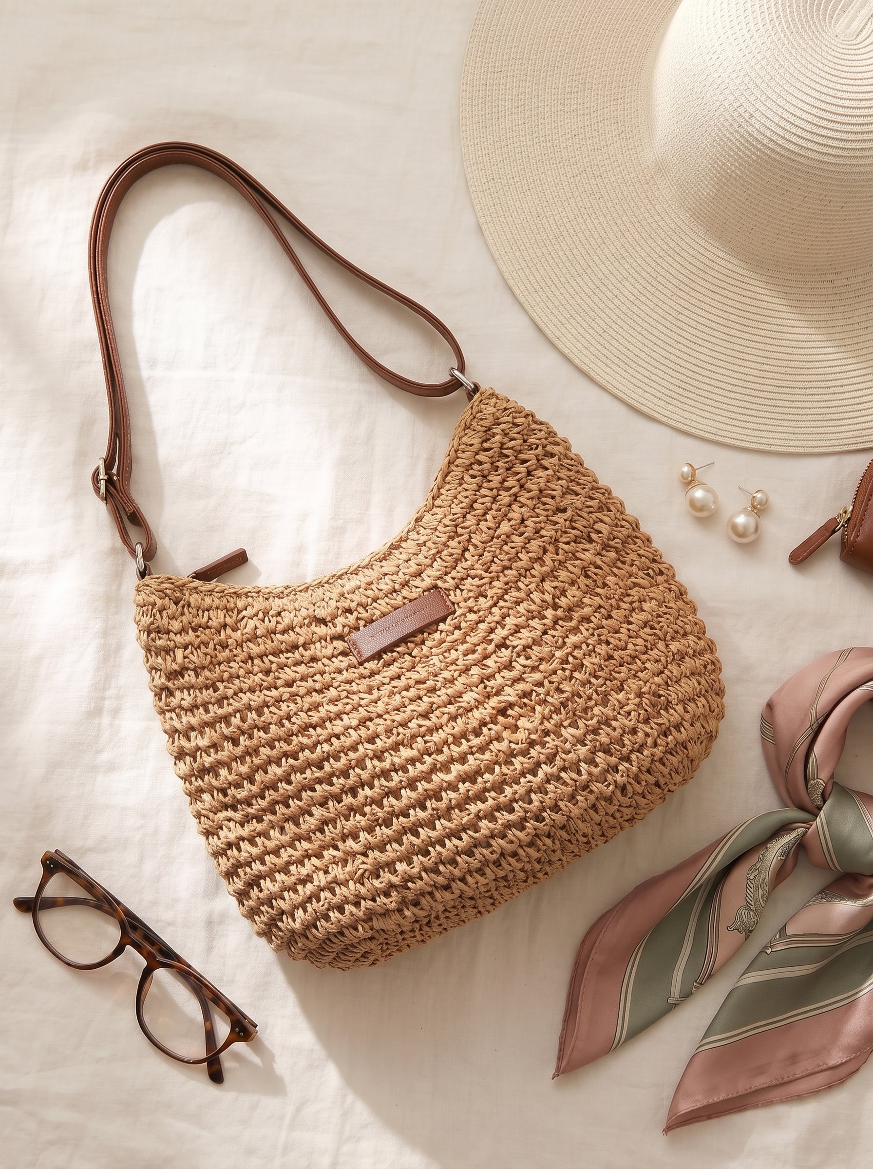 Bolso bandolera tejido camel con asa de cuero marrón y etiqueta frontal oscura