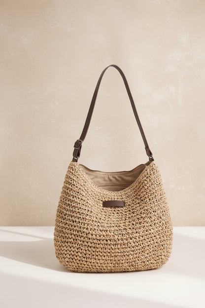 Bolso tejido beige con asa de cuero marrón y etiqueta frontal rectangular