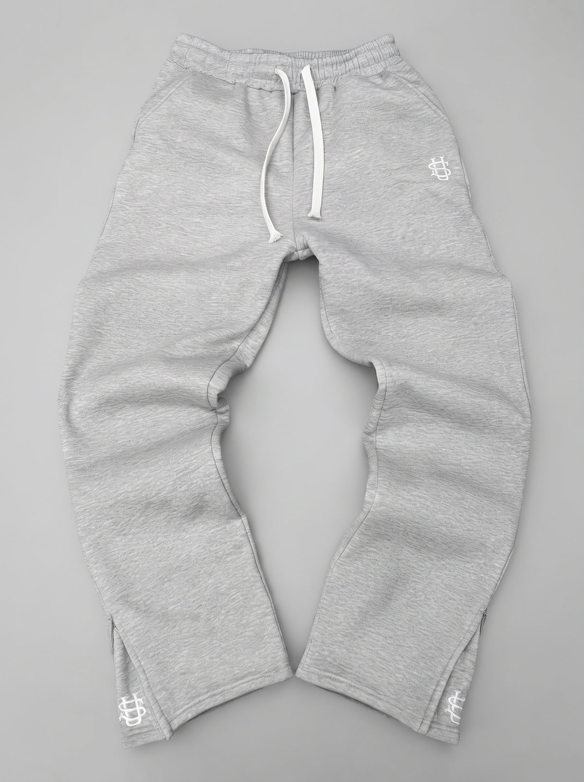 Pantalón chándal gris oversize con cordón blanco, puños elásticos y logos en los bajos