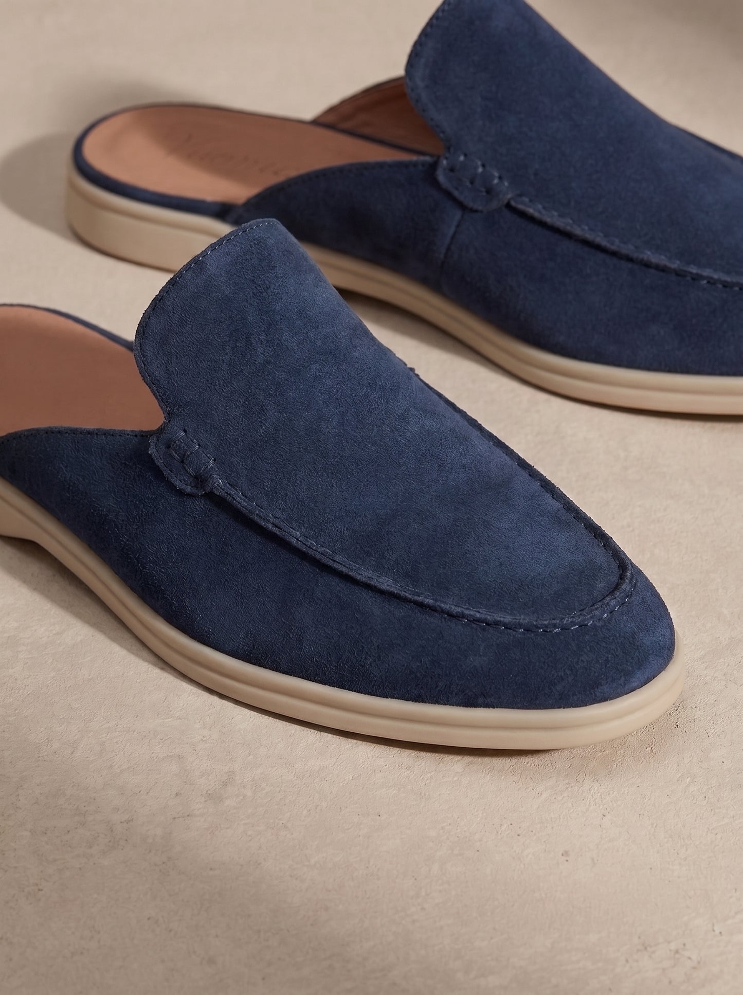 Mocasín mule de ante azul con costuras decorativas y suela beige.