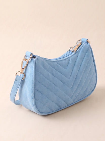 Bolso mini celeste con pompón blanco y asa con cadena dorada, acolchado zigzag