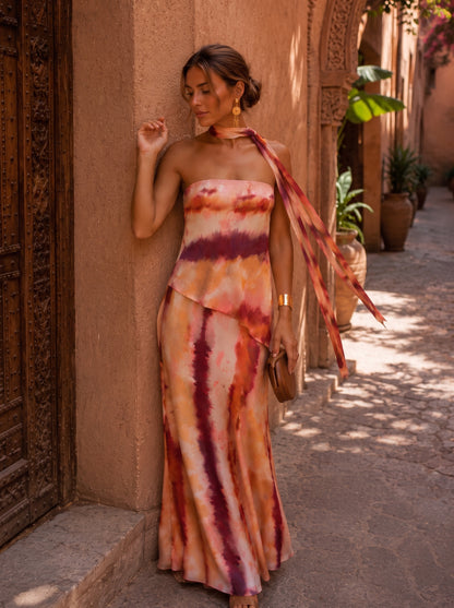 Vestido largo estampado con escote halter y lazo; diseño vertical en terracota, blanco y morado.