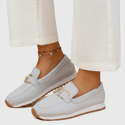 Zapatilla mocasín gris claro de malla con hebilla dorada y suela marrón