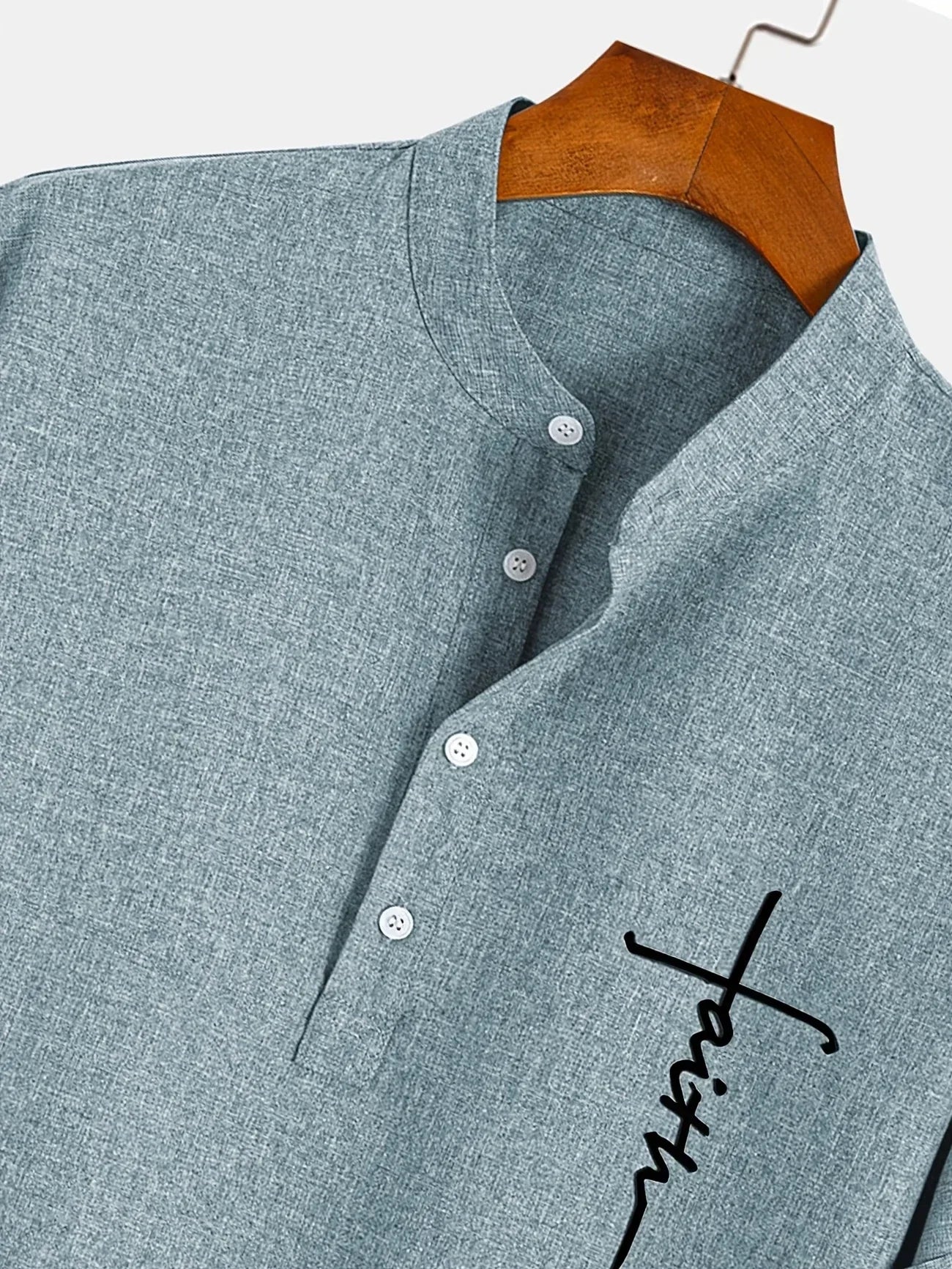 Camiseta azul cielo con cuello mao, tapeta de botones y estampado cruz lateral.