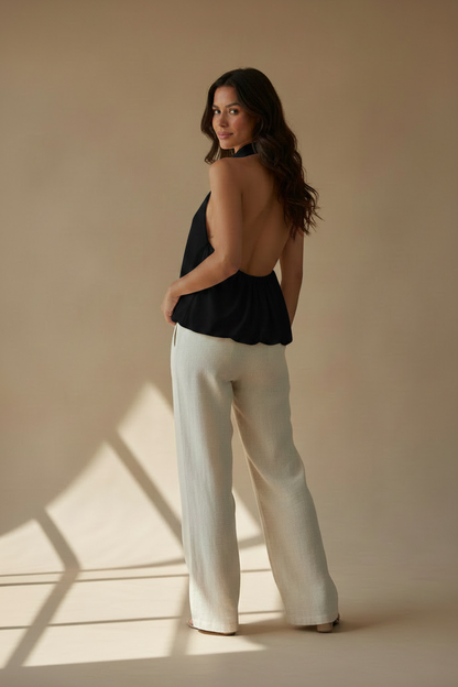 Top halter negro sin mangas, con cuello alto y caída amplia; espalda con tirantes.